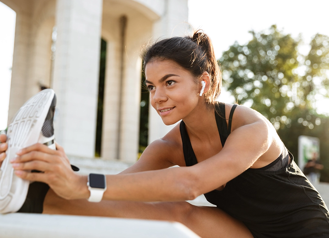 Mujer alegre haciendo estiramientos previos a su rutina de running